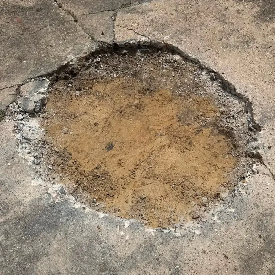 A clean round opening cut through the concrete slab, backfilled with soil and ready to plant