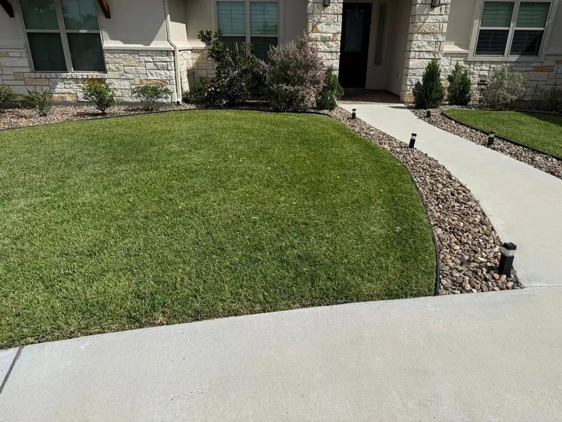 A home entry walkway with trimmed shrubs and a clean rock border