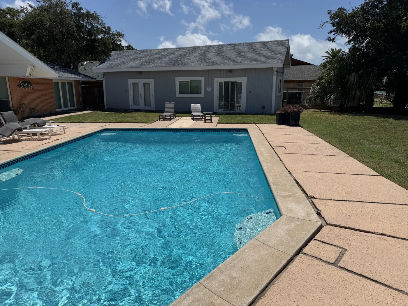 A backyard pool bordered by mowed lawn and clean patio
