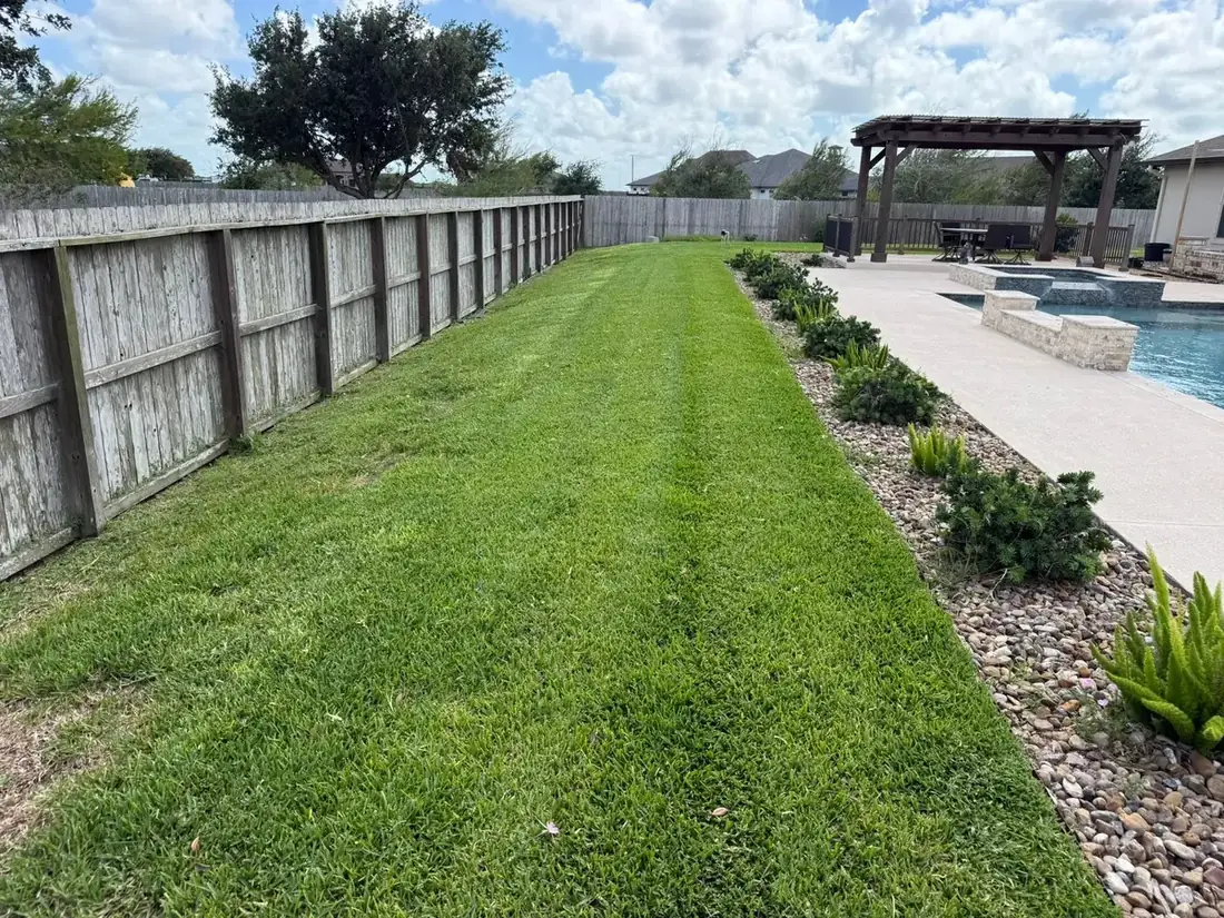 A poolside lawn strip mowed and edged beside a planted rock bed