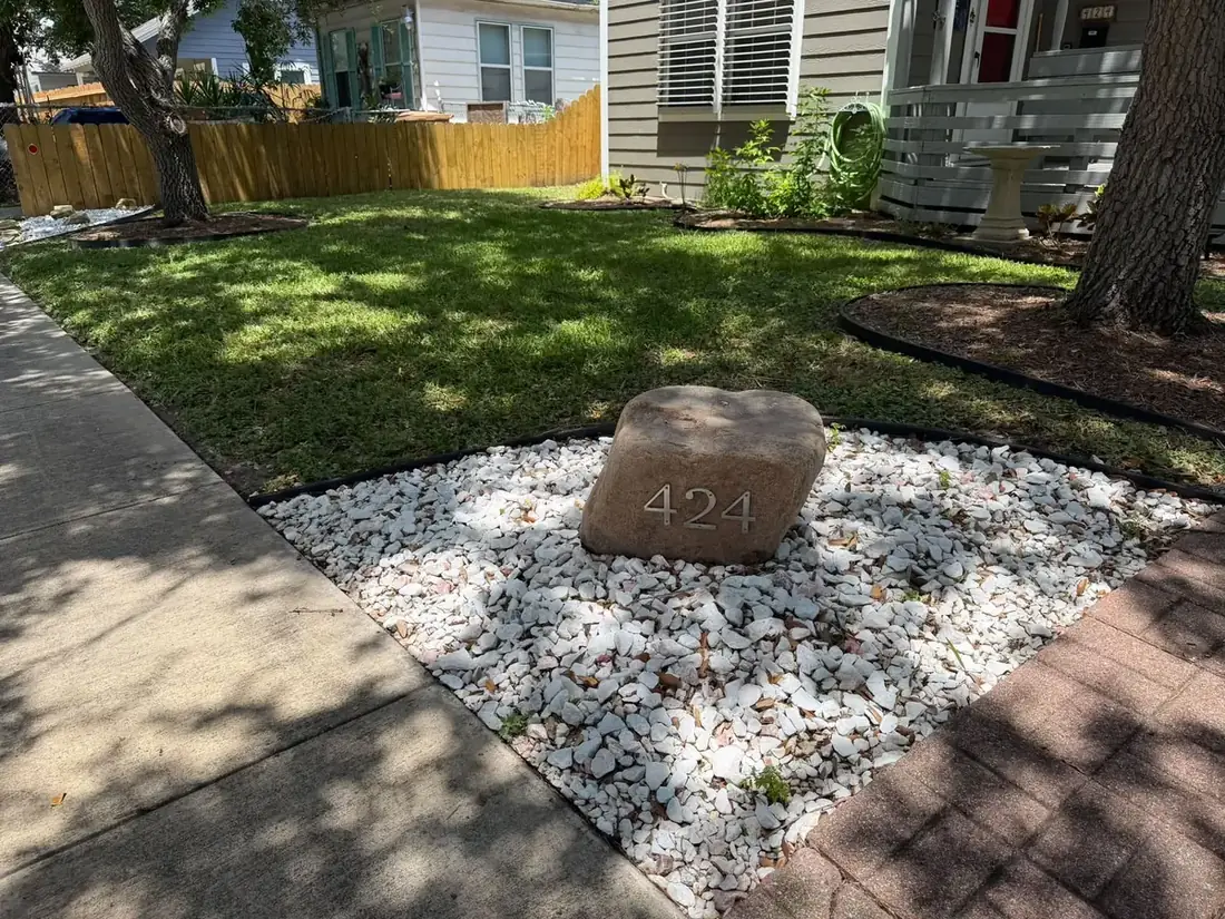 A white rock bed built around a tree with an address stone set in the middle