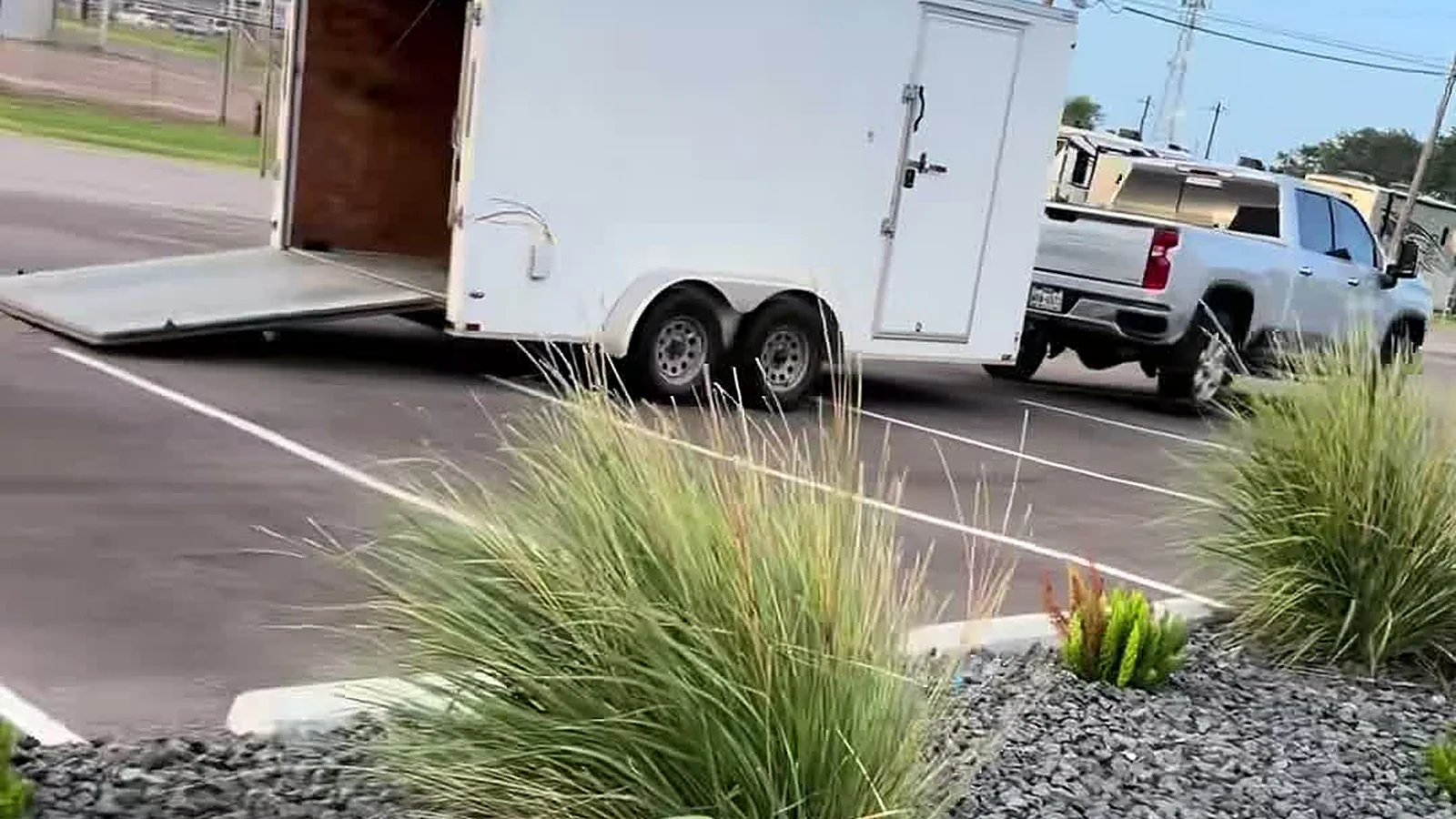 LRT's truck and enclosed trailer at a commercial property, fresh rock beds and ornamental grasses in the foreground