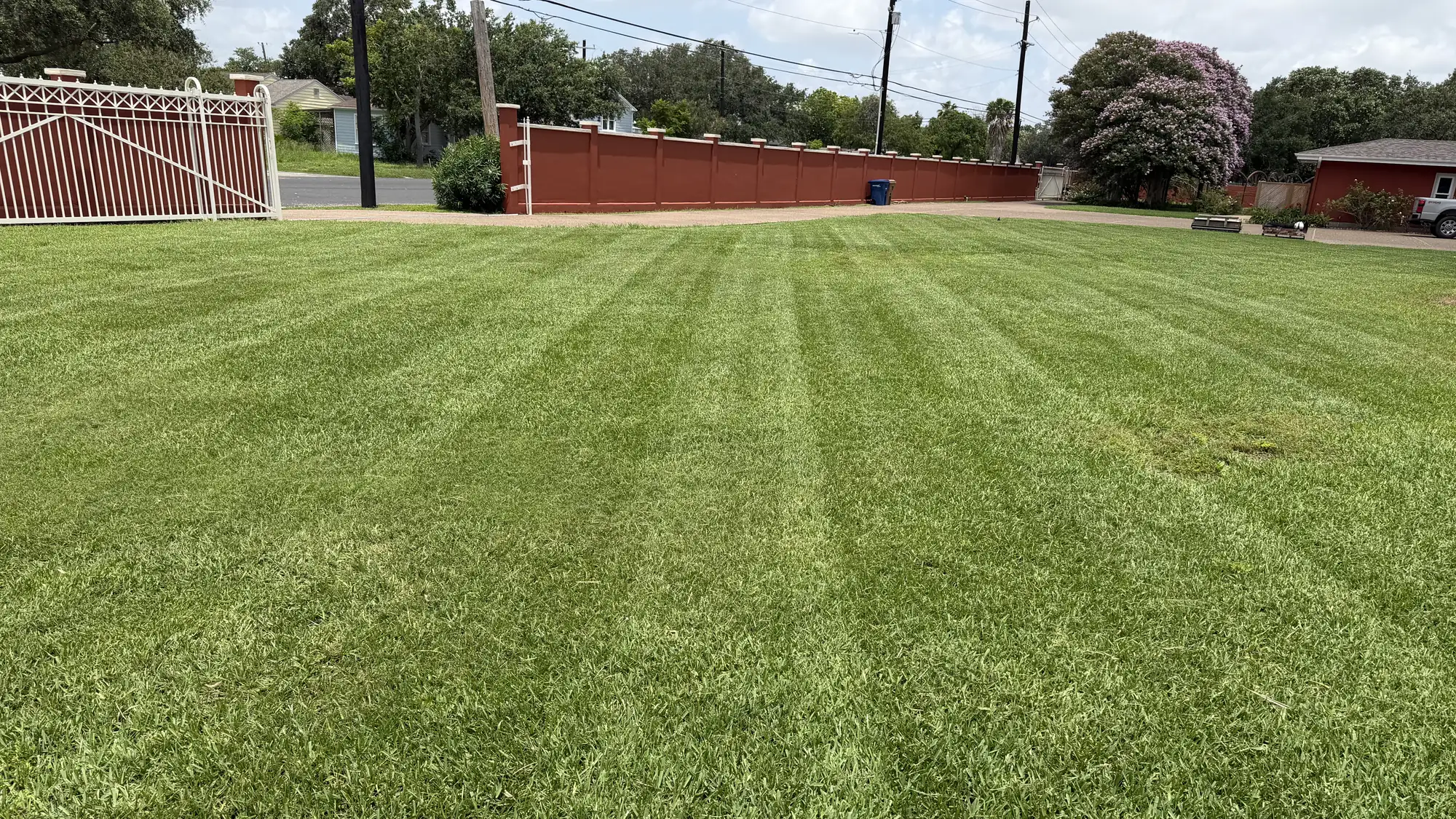 A wide residential lot in Portland, Texas mowed into clean stripes by LRT Lawn Care & Landscaping